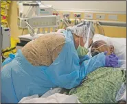  ?? (AP/Jae C. Hong) ?? Romelia Navarro, 64, weeps while hugging husband Antonio in his final moments in a covid-19 unit at St. Jude Medical Center in Fullerton, Calif., on July 31. Photograph­er Jae C. Hong said even though he had the family’s consent to be there, he struggled to shoot the intimate scene, feeling uneasy to even pick up his camera and document the end of someone’s life. “Capturing someone else’s painful emotion never gets easier,” Hong said. “What I saw that day still haunts me from time to time.”