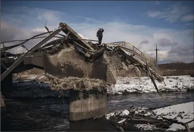  ?? ?? A man stands atop a destroyed bridge March 8 in Irpin, on the outskirts of Kyiv, Ukraine.