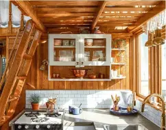  ??  ?? Kyla kept the tugboat’s original wood panelling but used subway tiles and a concrete-like countertop to give the kitchen an edgy look