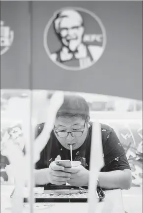  ?? BLOOMBERG ?? A customer uses a mobile phone while eating at a KFC restaurant in Shanghai.