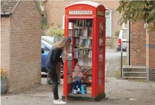  ?? — Reuters ?? Aria Casey, 2, looks at books in a library inside a former British Telecom phone box in Long Clawson, Britain, on Monday.