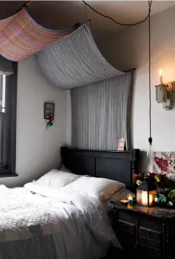  ??  ?? SPARE BEDROOM A striped beach windbreak creates a striking canopy over the bed. On the bedside table, a gleaming array of baubles and candles creates a festive feel. One of Anna’s stunning Scandiinsp­ired knitted jumpers is kept on display