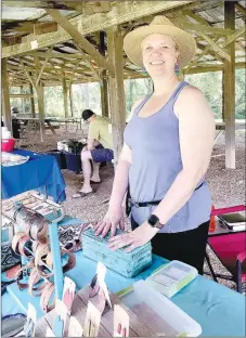  ?? SALLY CARROLL/MCDONALD COUNTY PRESS ?? Lisa Florey shows off her leather items that she has created. Florey started designing and working with leather, designing bags and jewelry, after she needed a bag to use while trail riding on her horse. Her company is expanding and Florey has enjoyed a great deal of success. She shows and sells her items at the Powell and Pineville Farmers Markets.
