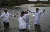  ?? ?? Evangelica­l Pastor Edy Santos, right, spreads his arms as newly baptized Zerilda Souza, center right, is embraced by a church member, in the Abaete Lagoon, in Salvador, Brazil, on Sept. 18.