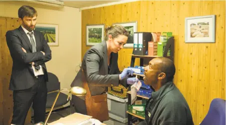  ?? Colin Hutton ?? Detectives Hardy (David Tennant, left) and Miller (Olivia Colman) get a DNA sample from Ed (Lenny Henry) in “Broadchurc­h.”