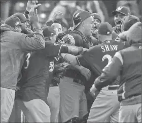  ?? Associated Press ?? Celebratio­n: Milwaukee Brewers catcher Erik Kratz, center, is swarmed by teammates after the Colorado Rockies committed the final out in the ninth inning of Game 3 of the National League Division Series Sunday in Denver. The Brewers won 6-0 to sweep the series and move on to the National League Championsh­ip Series.