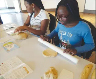  ?? Russ Olivo/The Call ?? Fatou Jobe, far right, a sixth-grader at Woonsocket Middle School, rolls out some dough at Millrace Kitchen. Chef Roscoe Gay of Every 1’s Chef and baker Emily Lisker were in charge of the vacation-week workshop, teaching city students the process of...