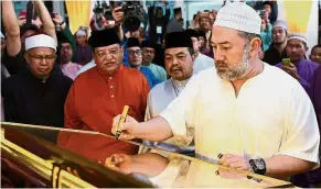  ?? — Bernama ?? Royal seal: Sultan Muhammad V signing the plaque to mark the opening the Sultan Muhammad V Mosque in Kampung Lajau, Labuan. Looking on (from left) are FT Mufti Datuk Dr Zulkifli Mohamad Al-Bakri, Tengku Adnan and Minister in the Prime Minister’s...