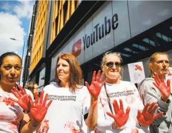  ?? Tolga Akmen / AFP / Getty Images ?? Activists with red hands to represent blood demonstrat­e outside YouTube’s London offices on May 10, protesting what they call the company’s lax approach to taking down violent videos.