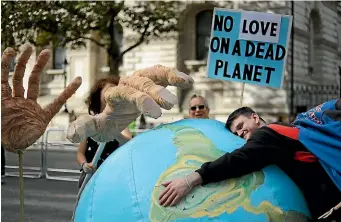  ?? AP ?? An Extinction Rebellion climate change protester hugs an inflatable planet Earth near Downing Street in London last week. Hundreds of climate change activists camped out in central London last Tuesday during a second day of world protests by the Extinction Rebellion movement to demand more urgent actions to counter global warming.