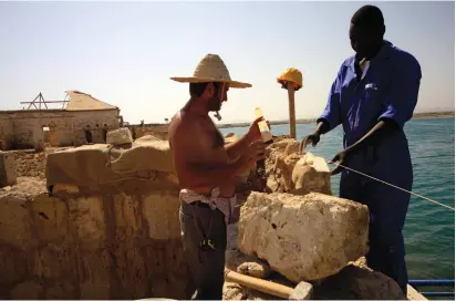  ??  ?? A TURKISH man assists a Sudanese worker in restoratio­n work in the Red Sea state of Suakin.