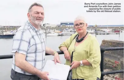  ??  ?? Burry Port councillor­s John James and Amanda Fox with their petition opposing the closure of public toilets by the old lifeboat station.