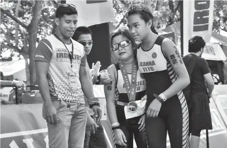  ?? MACKY LIM ?? I GOT YOU. Exhausted Rhexiel Belonguil, accompanie­d by an elder teammate, becomes emotional after crossing the finish line yesterday during the Alaska Ironkids triathlon at the Azuela Cove in Davao City. Rhexiel finished second in the 6-8 years old age...