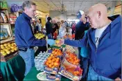  ??  ?? Jim Luft hands a man a fresh pear at the Sprouts Farmers Market booth at the Winter Visitor Welcome Back Bash.