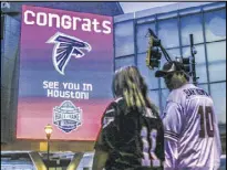  ?? JOHN SPINK / AJC ?? Tina and Matt Knight from Madison, Georgia, made their way along Marietta Street Monday near the College Football Hall of Fame. The Falcons advanced to their second Super Bowl in franchise history.