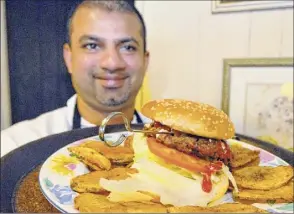  ?? MICHAEL P. FARRELL / TIMES UNION ?? Chef/owner Dave Khan holds a kabob burger with fresh chips at Burger Centric in Albany in 2009. Khan has recently opened Dave’s Gourmet Burgers and More, his fourth location.