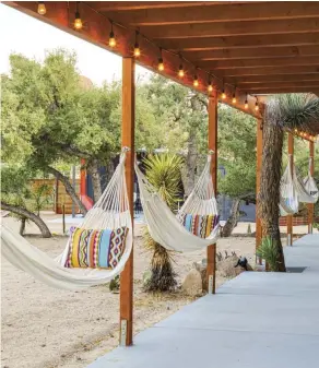  ??  ?? RIGHT: THE HAMMOCK GARDEN IS PLACED SO IT’S NOT IN FULL SUN, BUT YOU CAN STILL SEE THE STARS FROM YOUR PERCH AT NIGHT.
FUN FACT: THAT’S A JOSHUA TREE THE PORCH WAS BUILT AROUND. HOWEVER, AS OF FALL 2020, THE PLANT SPECIES IS PROTECTED UNDER THE CALIFORNIA ENDANGERED SPECIES ACT, SO IF YOU WERE BUILDING TODAY, YOU’D NEED TO GIVE MORE CLEARANCE. THE ICONIC TREES NEED OUR PROTECTION; THEY LIVE 150 YEARS ON AVERAGE AND HAVE BEEN DEVASTATED BY CLIMATE CHANGE AND LOSS OF HABITAT.
OPPOSITE: THE VIEW INTO THE MAIN HOUSE’S WELL- STOCKED KITCHEN.