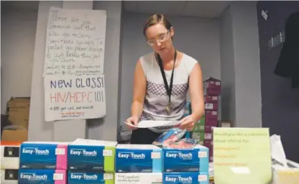  ?? Photos by Andy Cross, The Denver Post ?? Harm Reduction Action Center executive director Lisa Raville stands at the desk where heroin users come to exchange used syringes for new ones. The center also provides naloxone, the antidote to an opioid overdose.