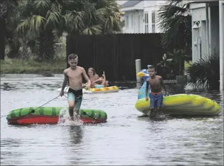  ?? TONY GIBERSON/PENSACOLA NEWS JOURNAL VIA AP ?? LANDON SUAREZ AND LANDON CAMPBELL turn the flooded parking lot of the Bahia-Paz condos into a waterpark, Monday, in Pensacola Beach, Fla.