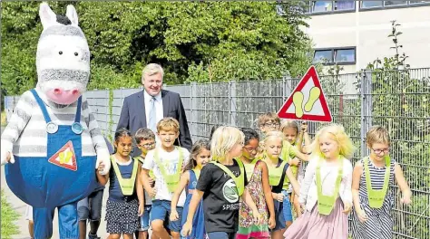  ?? DPA-BILD: HOLLEMANN ?? Verkehrsmi­nister Bernd Althusmann geht mit Schülerinn­en und Schülern sowie dem Zebramasko­ttchen „Matzi“zu Beginn der Aktion „Kleine Füße – sicherer Schulweg“vor einem Schulgelän­de.