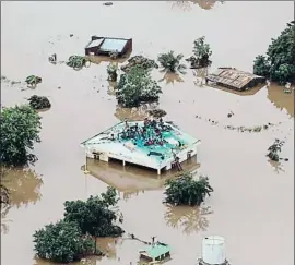  ?? RICK EMENAKET / AFP ?? Decenas de personas se refugian de las aguas en un tejado en Beira