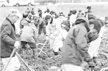  ??  ?? Firefighte­rs and town officials dig ground as they search for remains of victims of the 2011 Great East Japan earthquake in Namie, Fukushima prefecture on the seventh anniversar­y of the disaster. — AFP photo