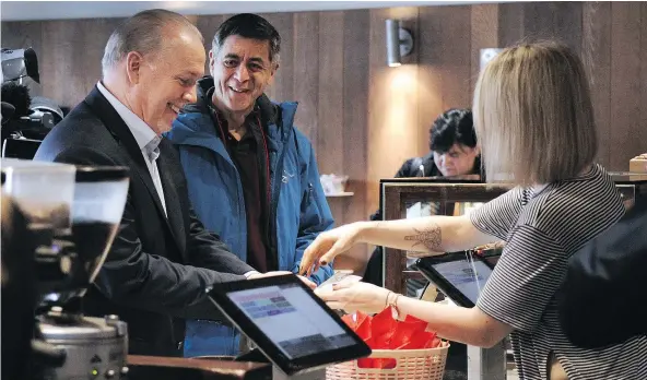  ?? NICK PROCAYLO ?? Premier John Horgan buys coffee at JJ Bean after making an announceme­nt regarding the minimum wage in North Vancouver on Thursday. The plan provides for an immediate increase of $1.30 an hour with a target of $15.20 an hour by June, 2021.