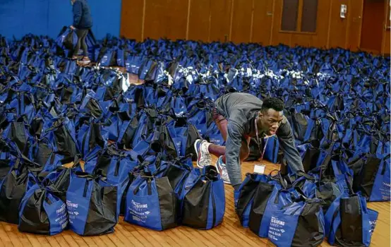  ?? JONATHAN WIGGS/GLOBE STAFF ?? A volunteer prepared bags of Thanksgivi­ng meal essentials at East Boston High School last year for their annual distributi­on.