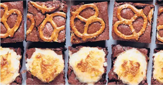  ?? YOSSY AREFI/THE NEW YORK TIMES ?? Stuffed or topped with the likes of sugared coconut, graham crackers or salted pretzels, these brownies are not about subtlety.