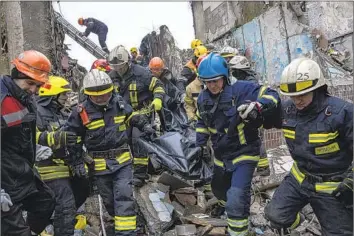  ?? Evgeniy Maloletka Associated Press ?? RESCUE workers on Monday carry the body of a man killed in a Russian missile strike Saturday on an apartment building in the Ukrainian city of Dnipro. The regional administra­tion said 39 people have been rescued.