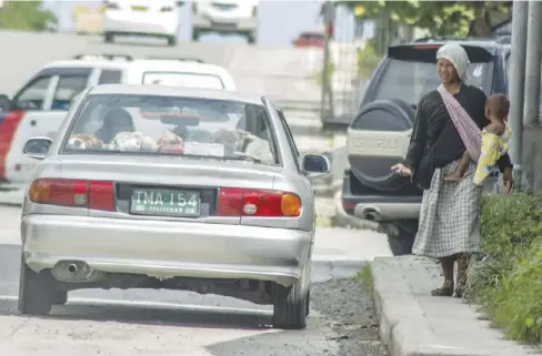  ??  ?? A Badijao woman begs for alms from a passing car on the circumfere­ntial road in Jaro, Iloilo City. The city government wants her and other Badjaos deported to Mindanao, citing public health and security concerns.