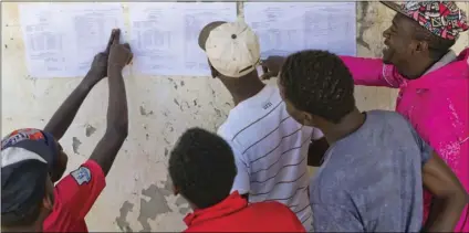  ?? AP PHOTO/JEROME DELAY ?? Zimbabwean­s check the results posted outside a polling station in Bulawayo, Zimbabwe. Zimbabwean­s on Tuesday awaited the first results from an election that they hope will lift the country out of economic and political stagnation after decades of rule...