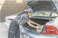  ?? MATT EDGE/THE NEW YORK TIMES ?? A worker demonstrat­es the delivery of an Amazon package to a vehicle’s trunk Monday.