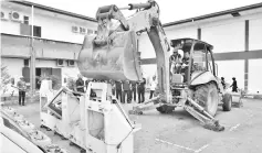  ??  ?? Zaini operating a backhoe loader to ‘crush’ the gambling machines before disposing them of through the e-waste method.