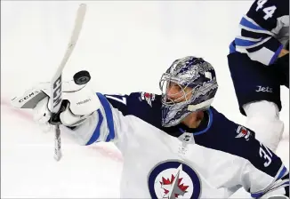  ?? Associated Press photo ?? Winnipeg Jets goaltender Connor Hellebuyck paddles the puck during the third period of an NHL hockey game against the Carolina Hurricanes, Sunday in Raleigh, N.C. Hellebuyck had 33 saves in the Jets' 3-2 win.