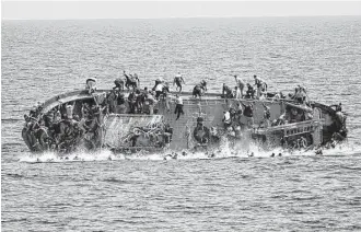  ?? Marina Militare photo via Associated Press ?? People jump out of a boat right before it overturns off the Libyan coast on Wednesday. Amid the continued flows of refugees and migrants to Europe, the German government announced an initiative to boost employment and assimilati­on with a...