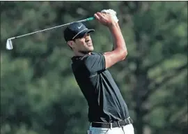  ?? Andrew Redington Getty Images ?? TONY FINAU, who dislocated his ankle celebratin­g a hole in one during the Par-3 Contest, hits his approach shot to the par-five 15th en route to a 68.