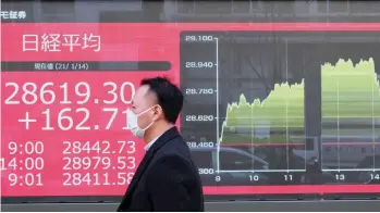  ?? — AFP ?? A pedestrian walks past an electronic quotation board displaying share prices on the Tokyo Stock Exchange in Tokyo.