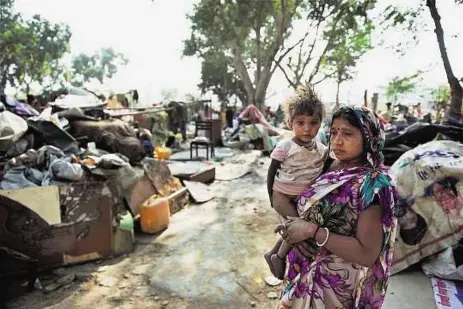  ?? PTI ?? Remains of a home A woman holds her child amid household items at Shakur Basti where a demolition drive was carried out in a slum in New Delhi yesterday. The hutments had been termed a health hazard.