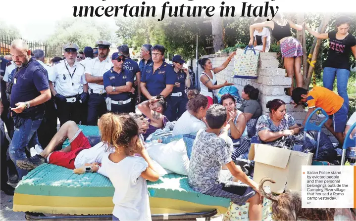  ?? AP ?? ■ Italian Police stand by evicted people and their personal belongings outside the Camping River village that housed a Roma camp yesterday.