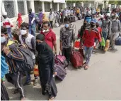  ?? — PTI ?? Migrants stand in queues as they wait to get on a bus for a railway station in Ahmedabad on Friday.