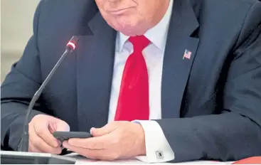  ?? Saul Loeb, AFP/Getty Images file photo ?? In this June file photo, then-President Donald Trump uses his cellphone during a meeting in the State Dining Room of the White House.