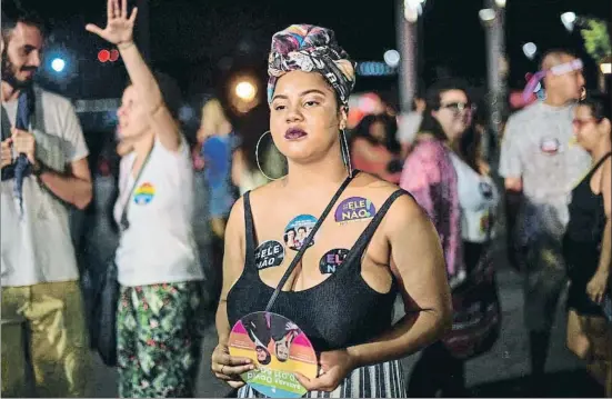  ?? CARL DE SOUZA / AFP ?? Una joven con pegatinas que dicen “él no”, en alusión a Bolsonaro, en una protesta contra el candidato ultraderec­hista el pasado sábado en Río