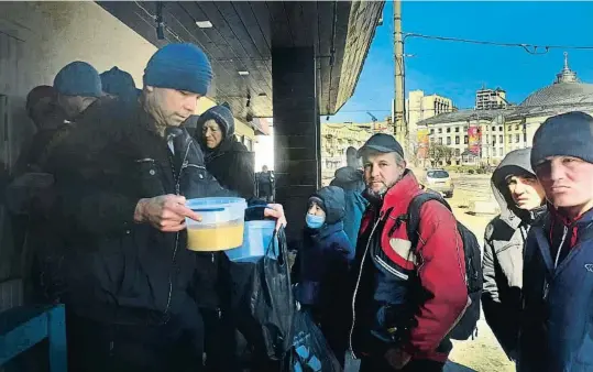  ?? JOAQUÍN LUNA ?? En Roman, de 45 anys (jaqueta vermella), fa tres anys que viu al carrer de Kíiv, on ahir donaven menjar al restaurant georgià Batumi