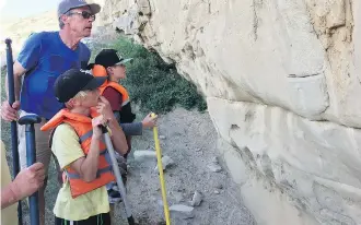  ??  ?? Former Bow River guide and driver Greg Zinter checks out rock carvings along the Bow with his grandchild­ren.