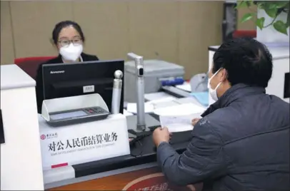  ?? WANG CHUN / FOR CHINA DAILY CHEN XIAOGEN / FOR CHINA DAILY ?? Above: A bank employee helps a customer with corporate settlement services at a Bank of China branch in Lianyungan­g, Jiangsu province, on Feb 24.
Left: Visitors check out a promotiona­l video for China Constructi­on Bank loan products during a financial expo in Beijing in October.