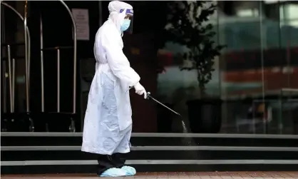  ?? Photograph: Hannah Peters/Getty Images ?? A hotel worker sanitises the outside of Stamford Plaza in Auckland, New Zealand, one of the country’s coronaviru­s quarantine facilities. The 30 deportees from Australia will be held at a secret isolation site.