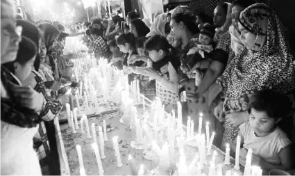  ??  ?? CATÓLICOS pakistaníe­s encienden velas en Karachi en memoria de los feligreses caídos en el ataque suicida talibán con bombas en un templo.