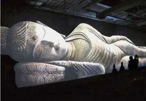  ??  ?? New age art: Visitors looking at a reclining Buddha image that was presented using 3D technology during an exhibition in Shanghai. — Photo provided to China Daily