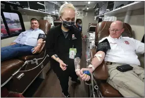  ?? (Arkansas Democrat-Gazette/Thomas Metthe) ?? Arkansas Blood Institute phlebotomi­st Elizabeth Brown draws blood Friday from Warren Almon as Shawn Spencer looks on during a city of North Little Rock drive.